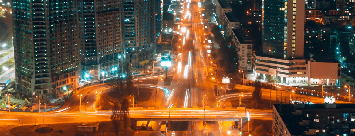 Night view of Gurgaon city skyline with illuminated roads, high-rise buildings, and traffic lights in Haryana.