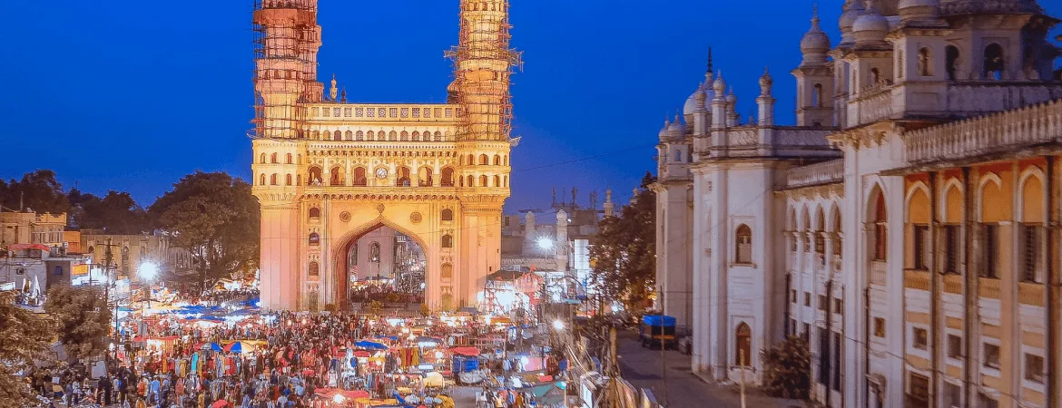 Charminar illuminated at night with bustling Laad Bazaar market in Hyderabad, Telangana.