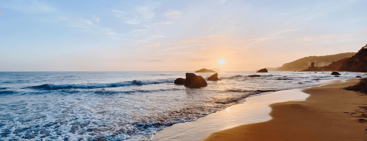 Sunrise at the beach in Visakhapatnam, Andhra Pradesh - scenic coastal view with golden sand, waves, and rocks by the sea.